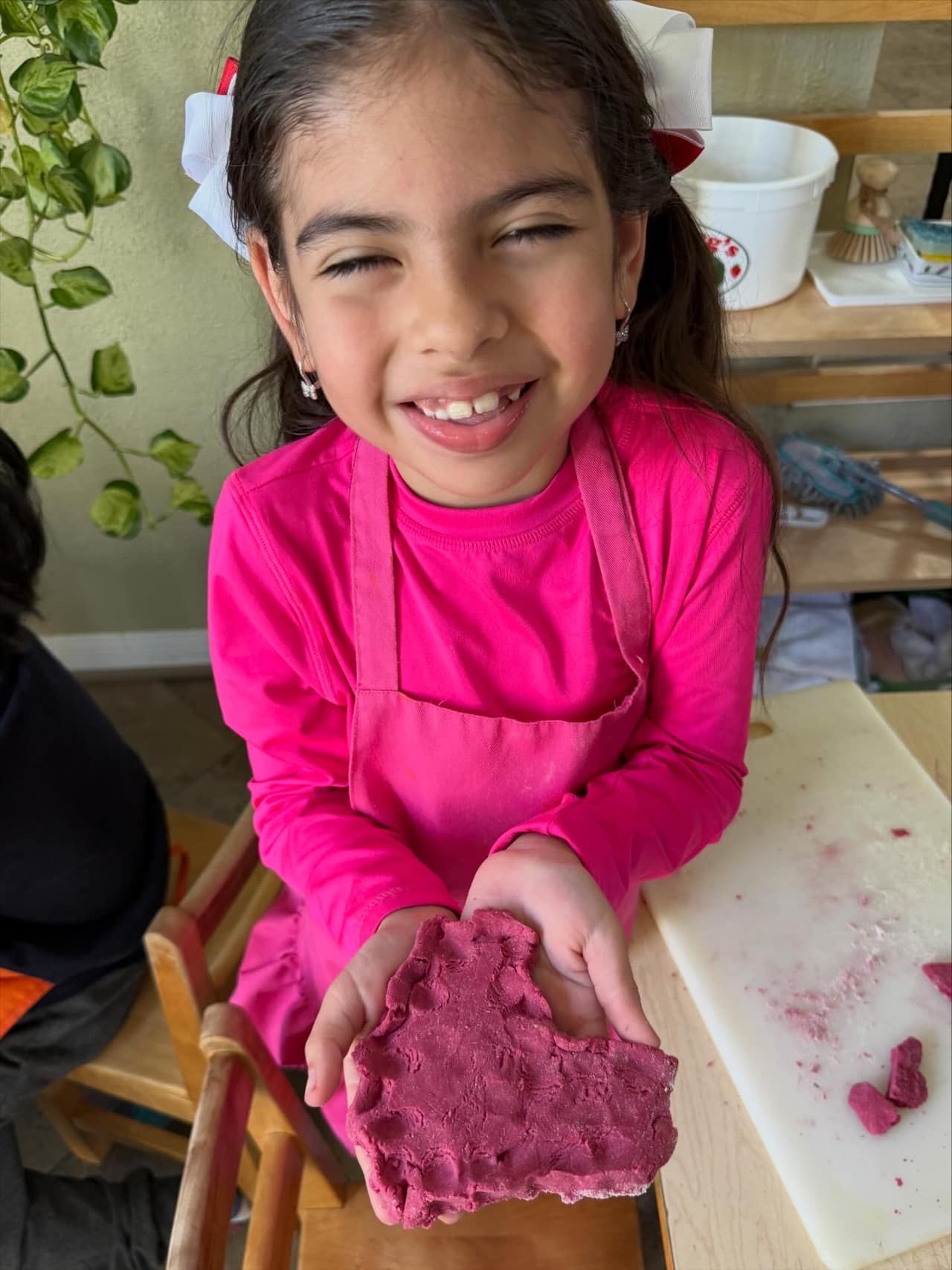A smiling Bayou Blossoms student holding her work